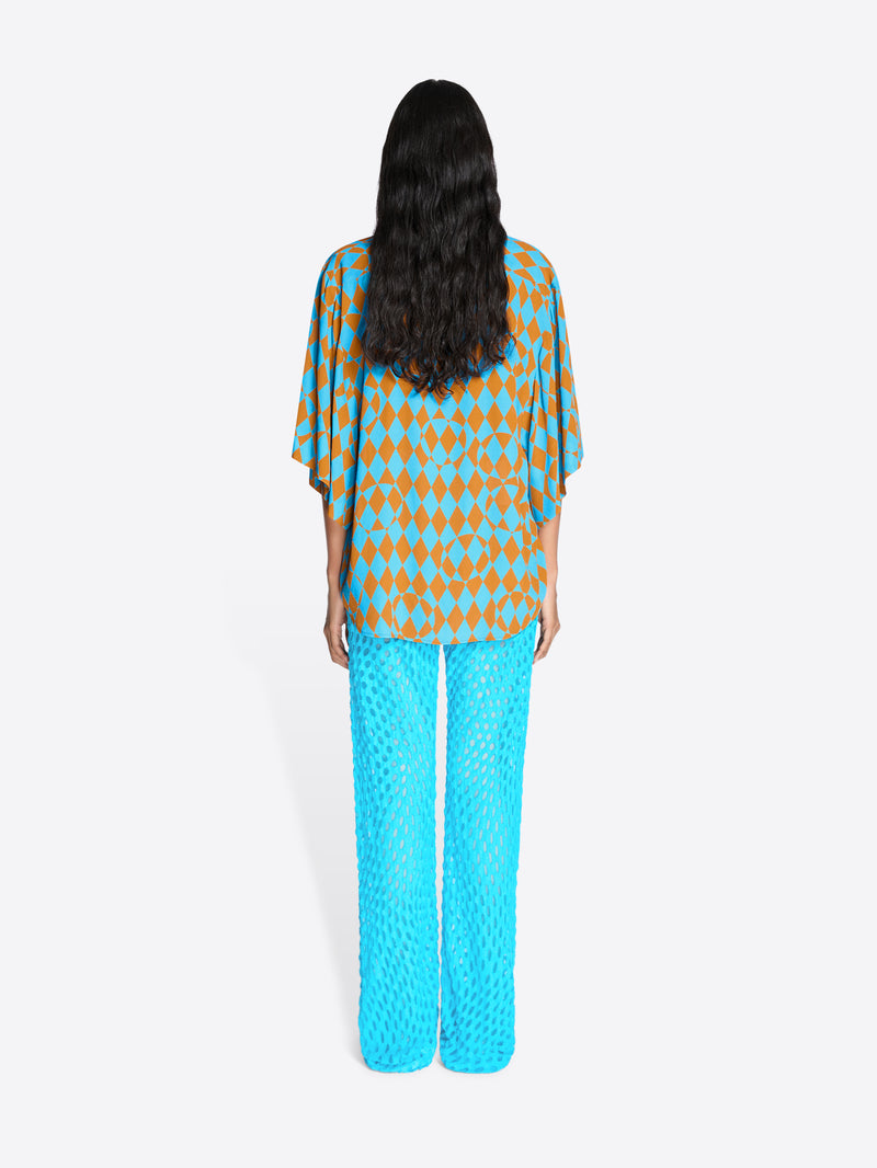 Person wearing a patterned top and bright blue pants on a white background - Dries Van Noten