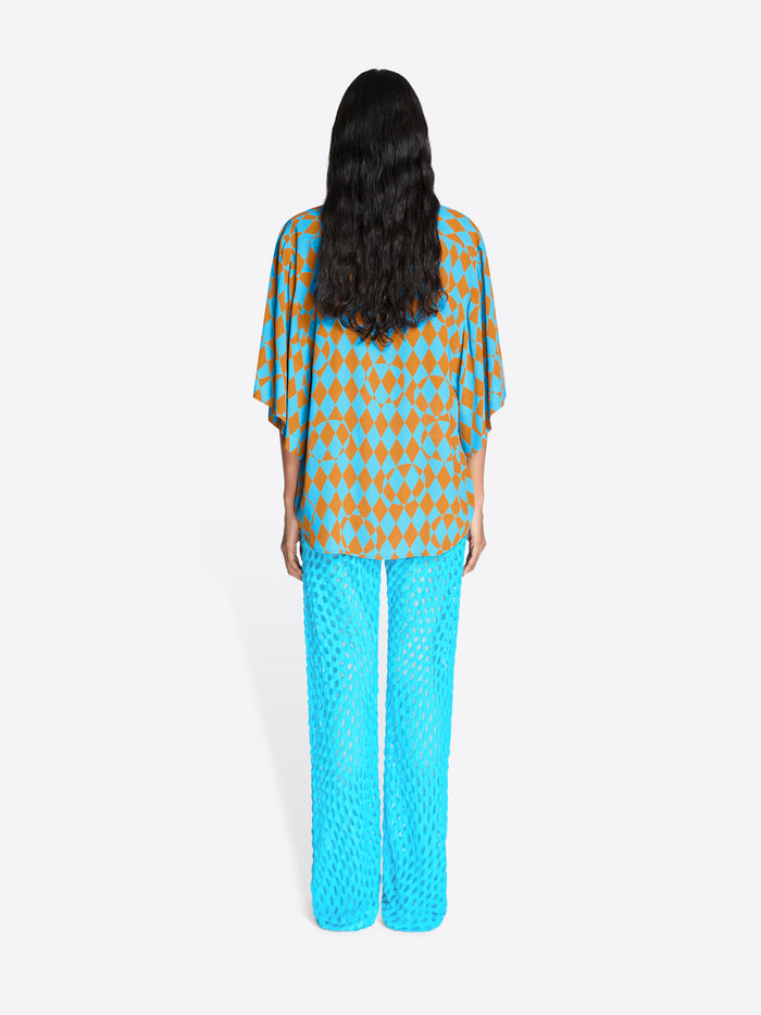 Person wearing a patterned top and bright blue pants on a white background - Dries Van Noten