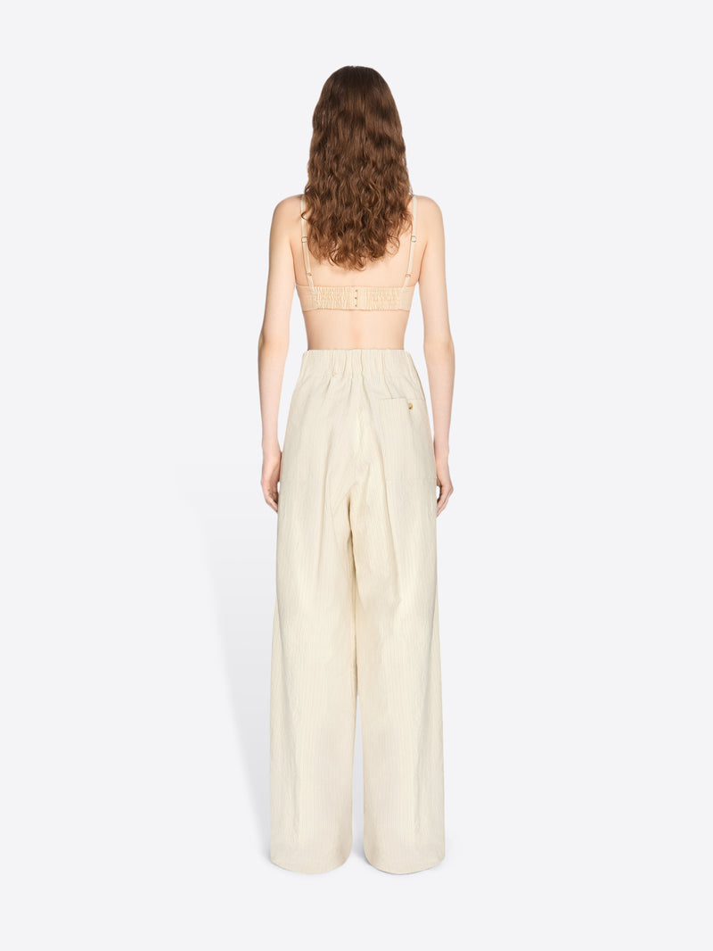 Woman wearing a strapless top and beige wide-leg pants on a white background - Dries Van Noten