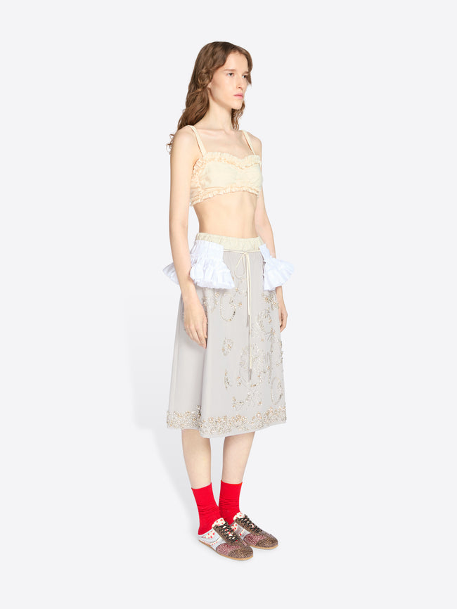 Woman wearing a beige lace top and skirt with red socks on a white background - Dries Van Noten