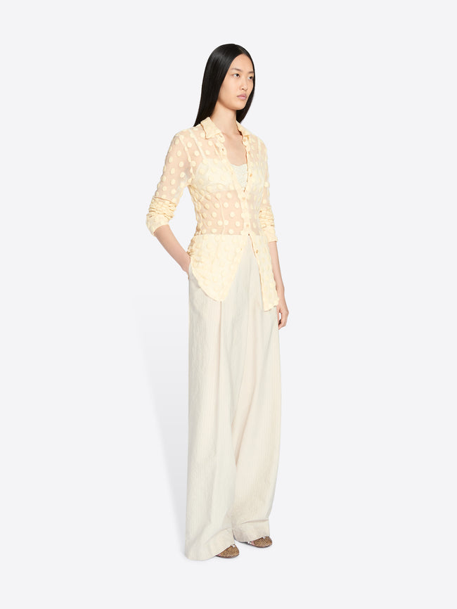 Woman wearing a light yellow top and white pants on a white background - Dries Van Noten