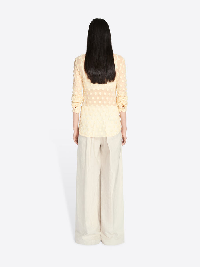 Person wearing a light yellow top and beige pants on a white background - Dries Van Noten