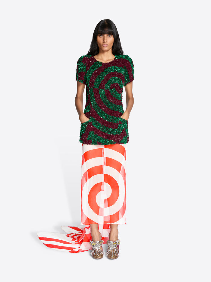 Woman wearing a green and red patterned top with a red and white striped skirt on a white background - Dries Van Noten