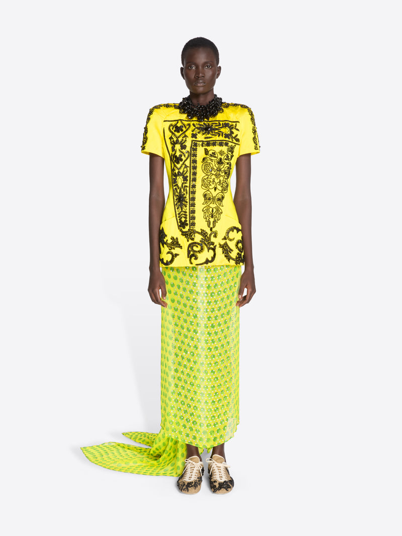 Model wearing a bright yellow outfit with black patterns on a white background - Dries Van Noten