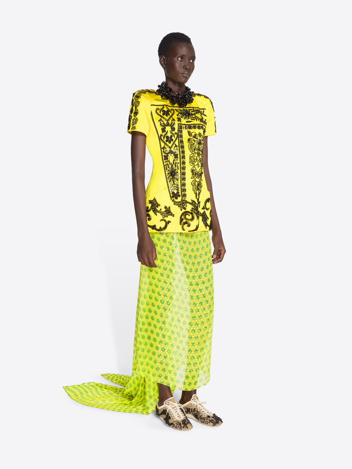 Model wearing a bright yellow and black patterned dress with a matching scarf on a white background - Dries Van Noten