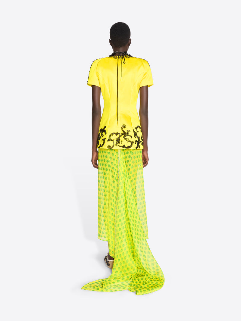 Model wearing a bright yellow dress with black floral patterns on a white background - Dries Van Noten