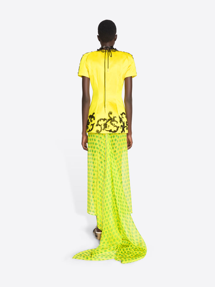 Model wearing a bright yellow dress with black floral patterns on a white background - Dries Van Noten