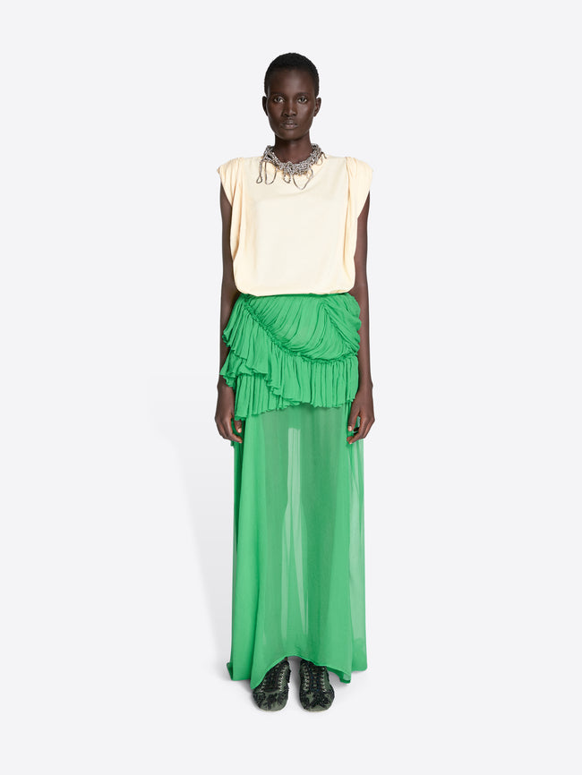 Model wearing a cream sleeveless top and green ruffled skirt on a white background - Dries Van Noten