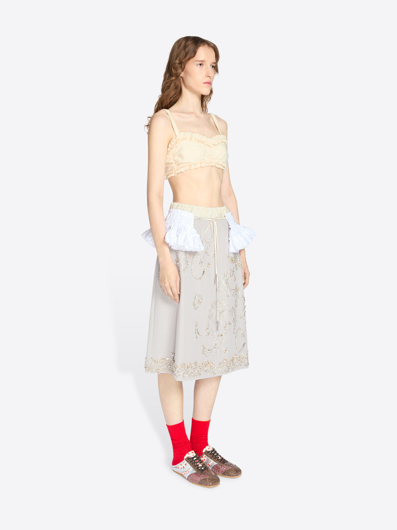 Woman wearing a beige lace top and skirt with red socks on a white background - Dries Van Noten