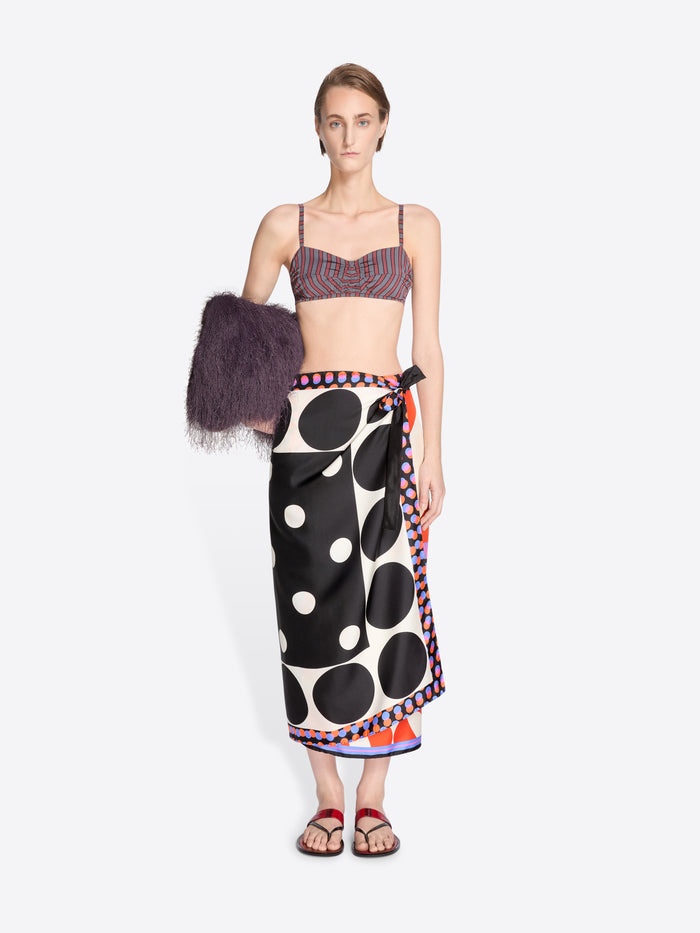Model wearing a patterned top and polka dot skirt with a fur coat on a white background - Dries Van Noten