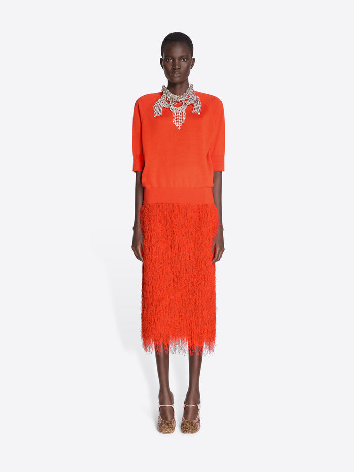 Model wearing a bright orange dress with a textured skirt and embellished neckline on a white background - Dries Van Noten