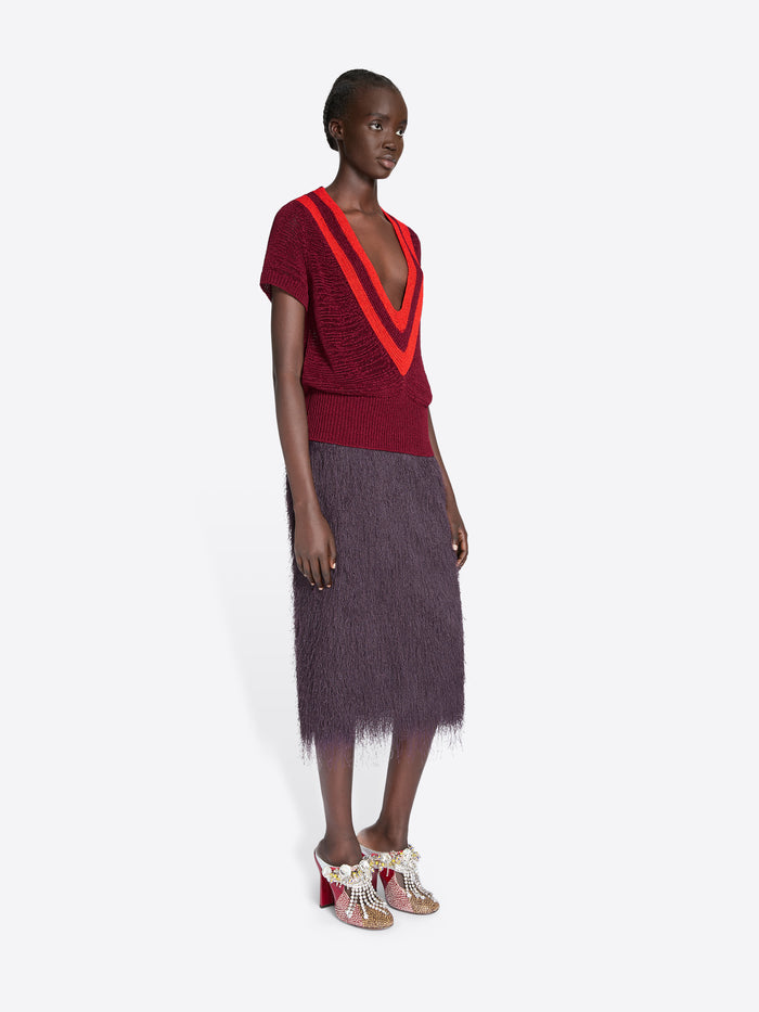 Model wearing a red top with a V-neck and a dark skirt on a white background - Dries Van Noten