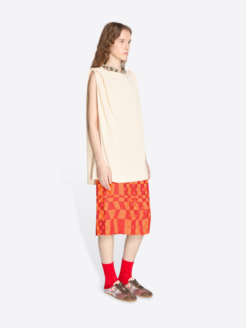 Woman wearing a beige top and red patterned skirt on a white background - Dries Van Noten