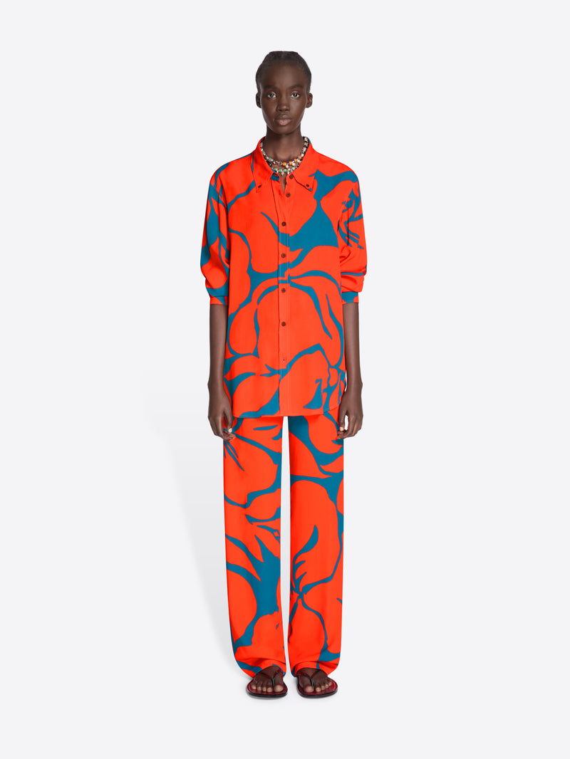 Person wearing a vibrant orange and blue patterned outfit on a white background - Dries Van Noten