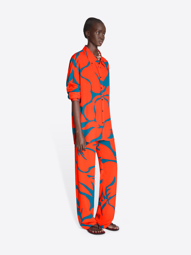 Person wearing a bright orange and blue patterned outfit on a white background - Dries Van Noten