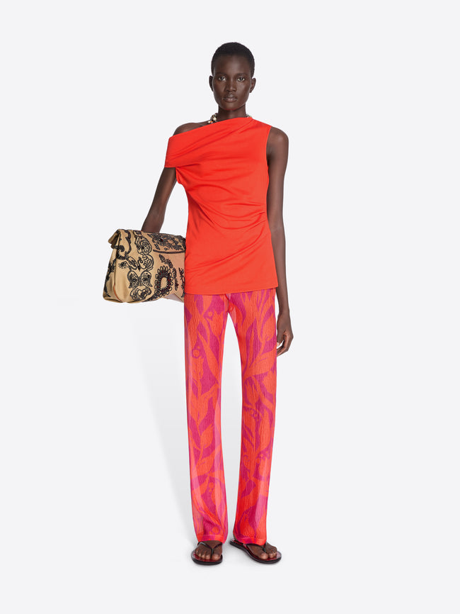Model wearing a bright orange top and pink patterned pants, holding a leopard print bag on a white background. - Dries Van Noten