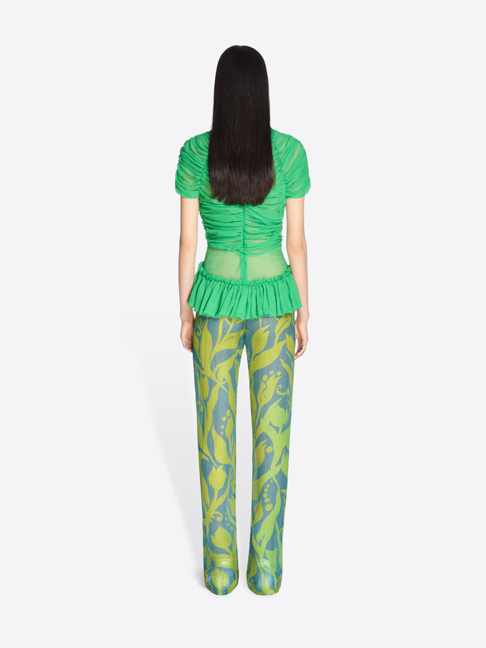 Person wearing a green top and patterned pants on a white background - Dries Van Noten