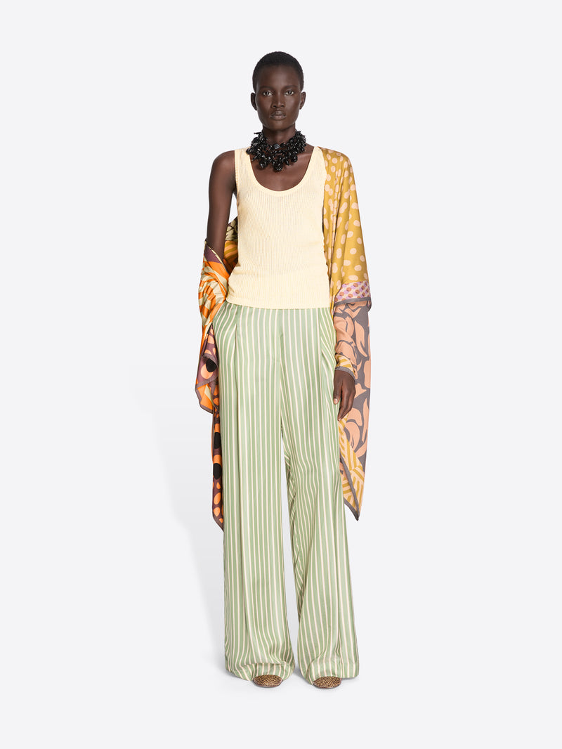 Model wearing a sleeveless top and wide-leg pants with a floral patterned garment over shoulders on a white background - Dries Van Noten