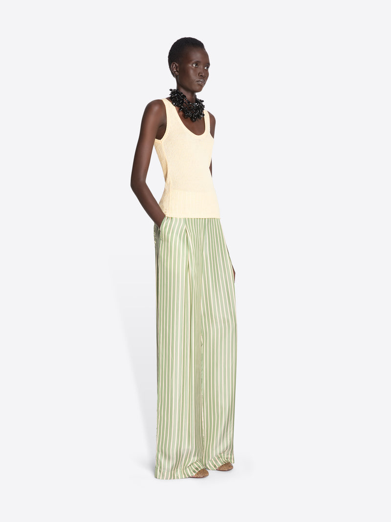 Model wearing a light-colored sleeveless top and green striped pants on a white background - Dries Van Noten