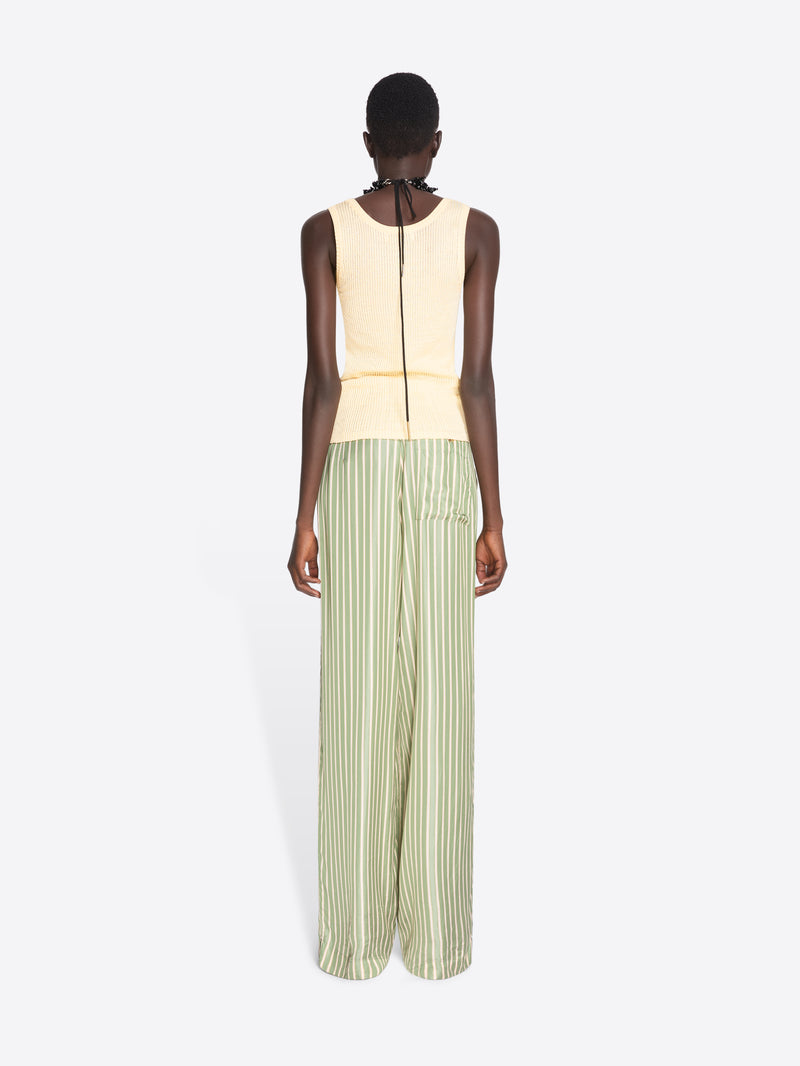Woman wearing a light-colored sleeveless top and green striped pants on a white background - Dries Van Noten