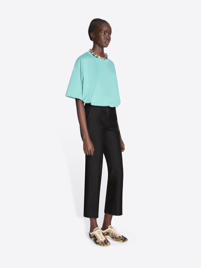 Person wearing a light blue top and black pants on a white background - Dries Van Noten