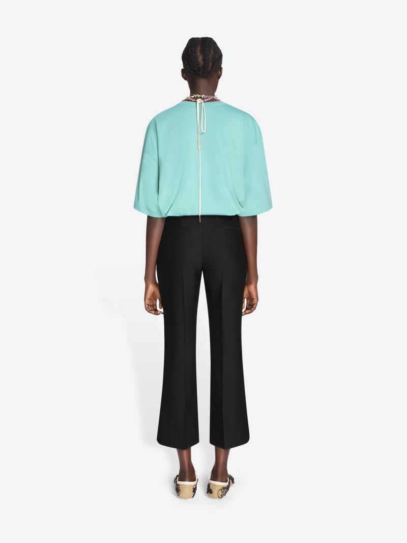 Person wearing a light blue top and black pants on a white background - Dries Van Noten