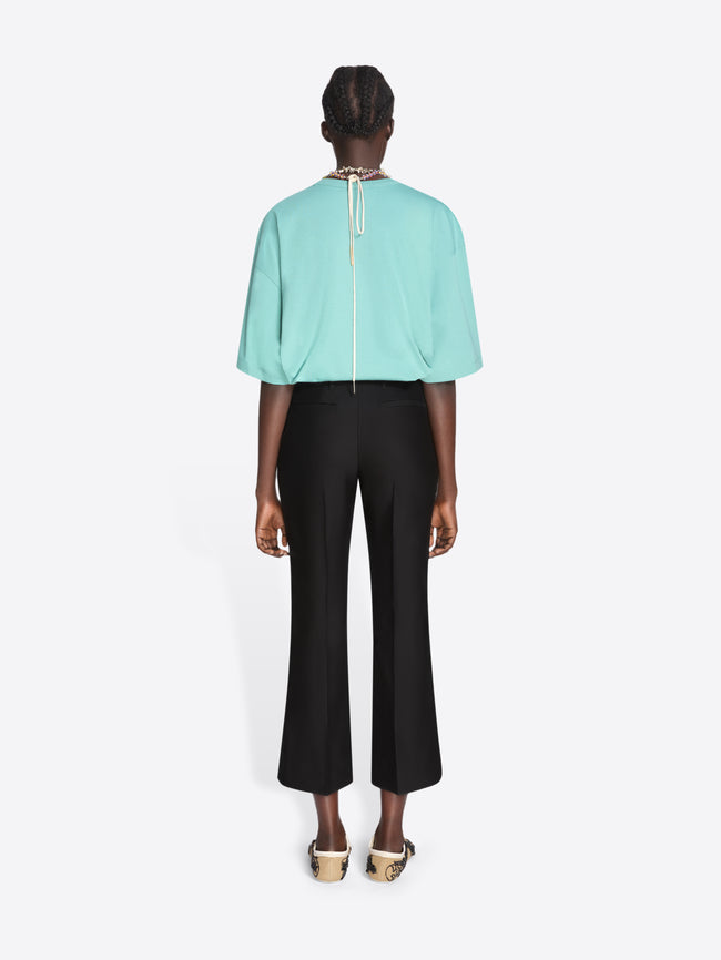 Person wearing a light blue top and black pants on a white background - Dries Van Noten