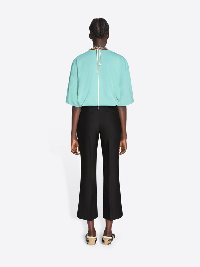 Person wearing a light blue top and black pants on a white background - Dries Van Noten