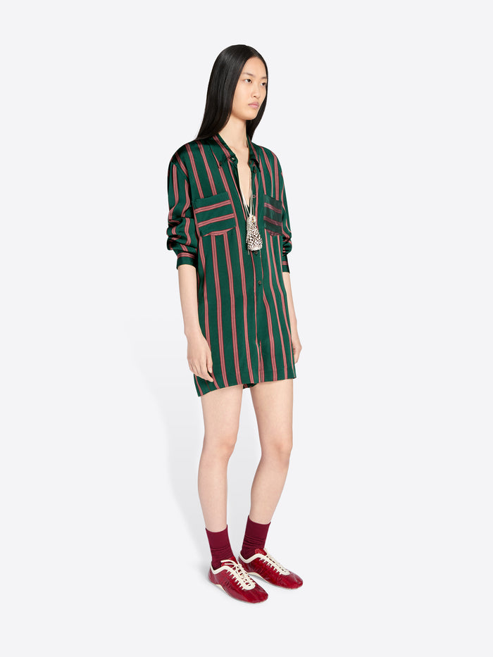 Woman wearing a green and red striped jumpsuit with red shoes on a white background - Dries Van Noten