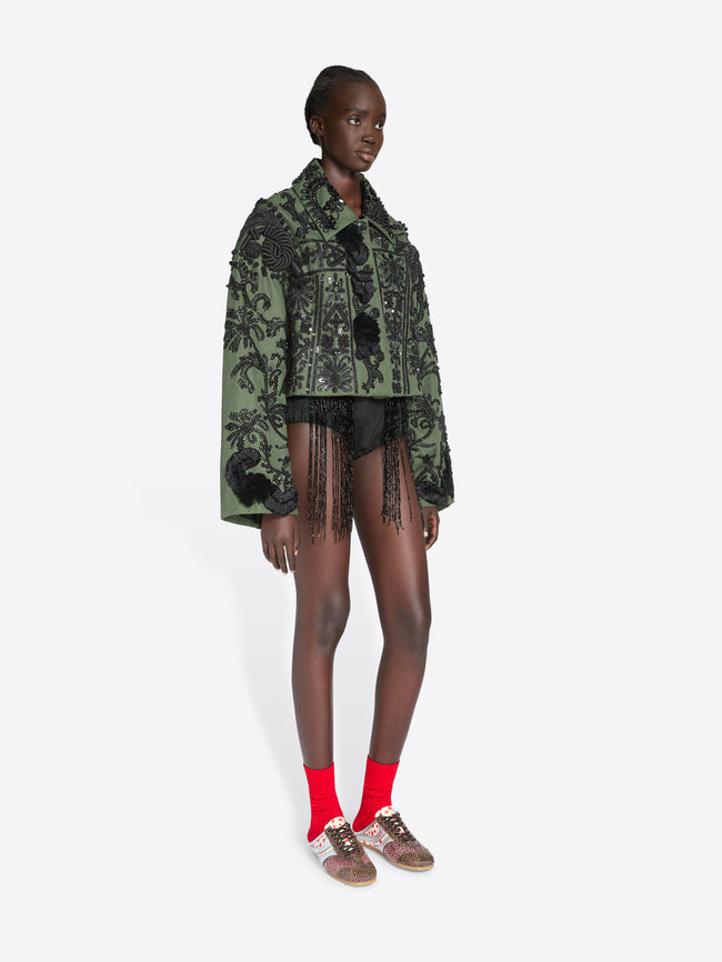 Model wearing a green patterned jacket with tassels on a white background - Dries Van Noten
