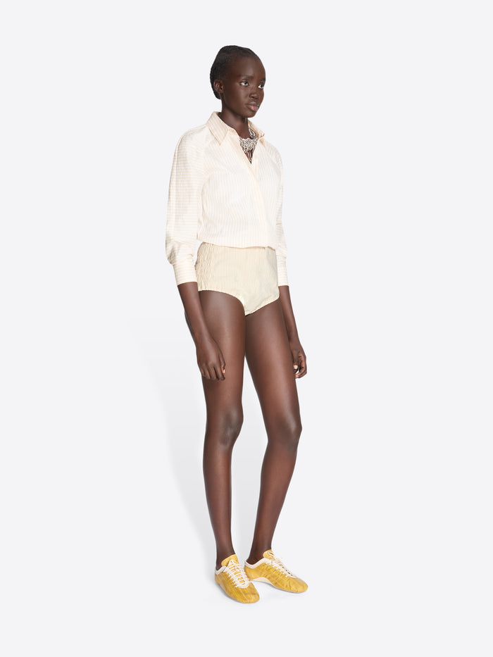 Person wearing a white shirt and beige shorts on a white background - Dries Van Noten