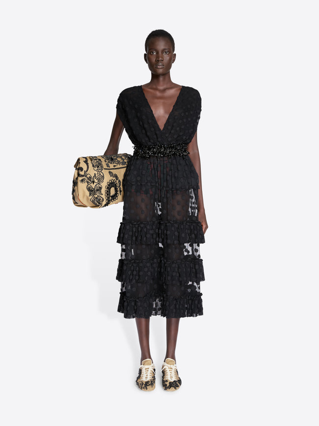 Model wearing a black lace dress holding a patterned handbag on a white background - Dries Van Noten