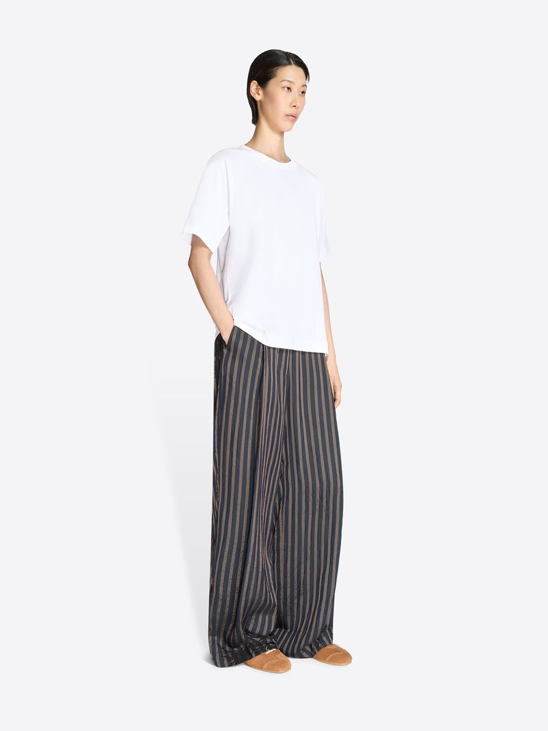 Person wearing a white top and striped pants on a white background - Dries Van Noten