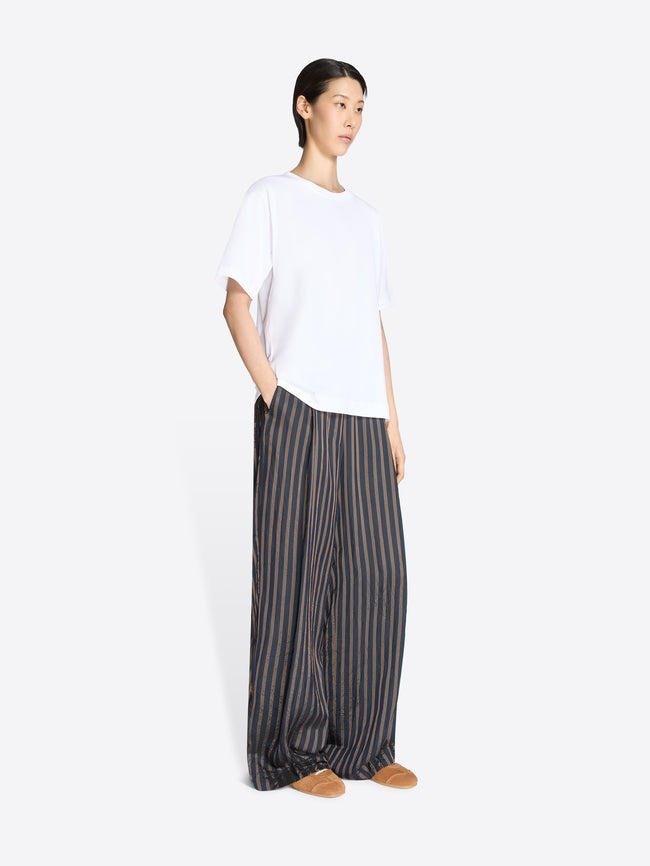 Person wearing a white top and striped pants on a white background - Dries Van Noten