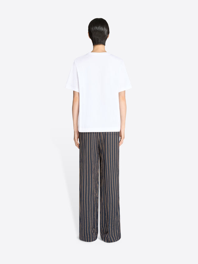 Person wearing a white t-shirt and striped pants on a white background - Dries Van Noten