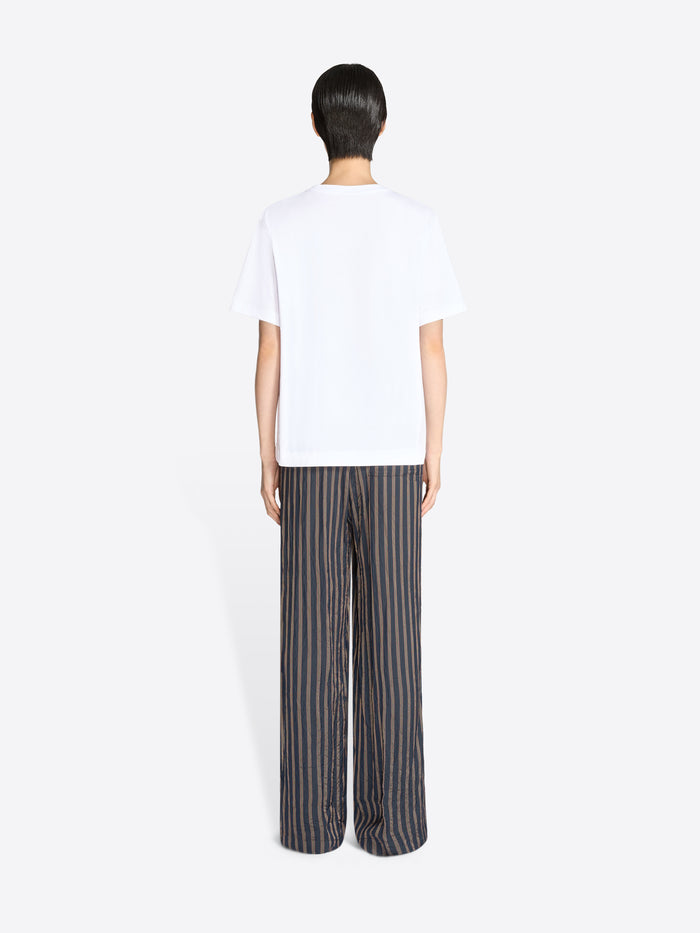 Person wearing a white t-shirt and striped pants on a white background - Dries Van Noten