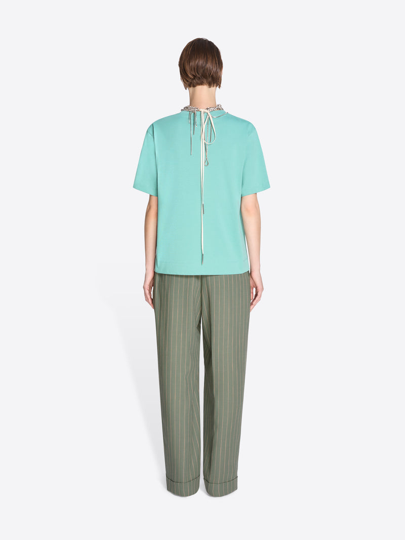 Person wearing a light blue top and green pants on a white background - Dries Van Noten