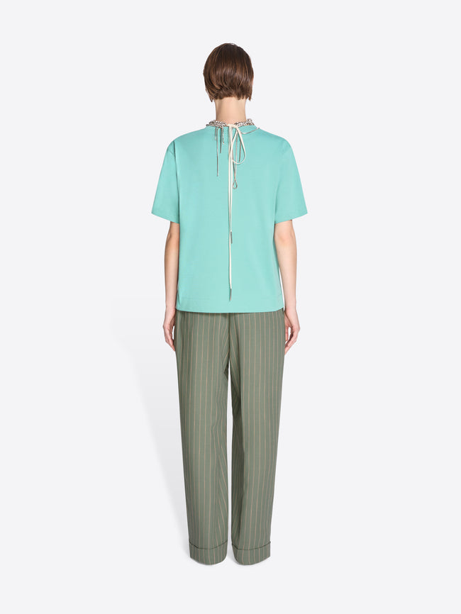 Person wearing a light blue top and green pants on a white background - Dries Van Noten