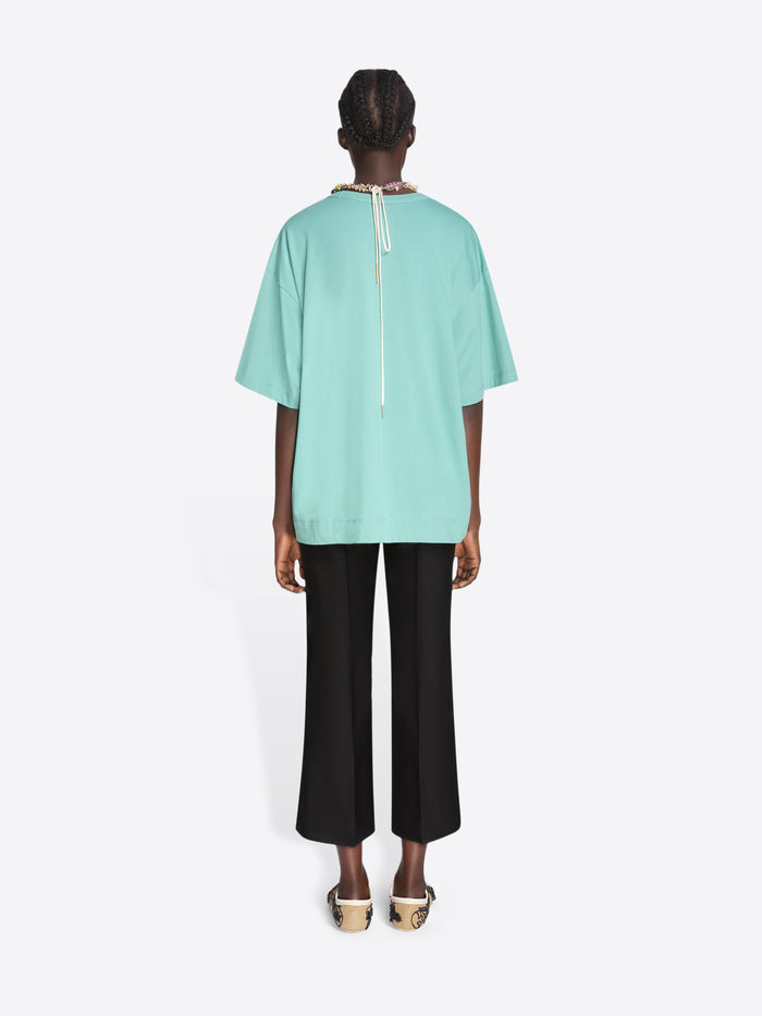 Person wearing a light blue top and black pants on a white background - Dries Van Noten