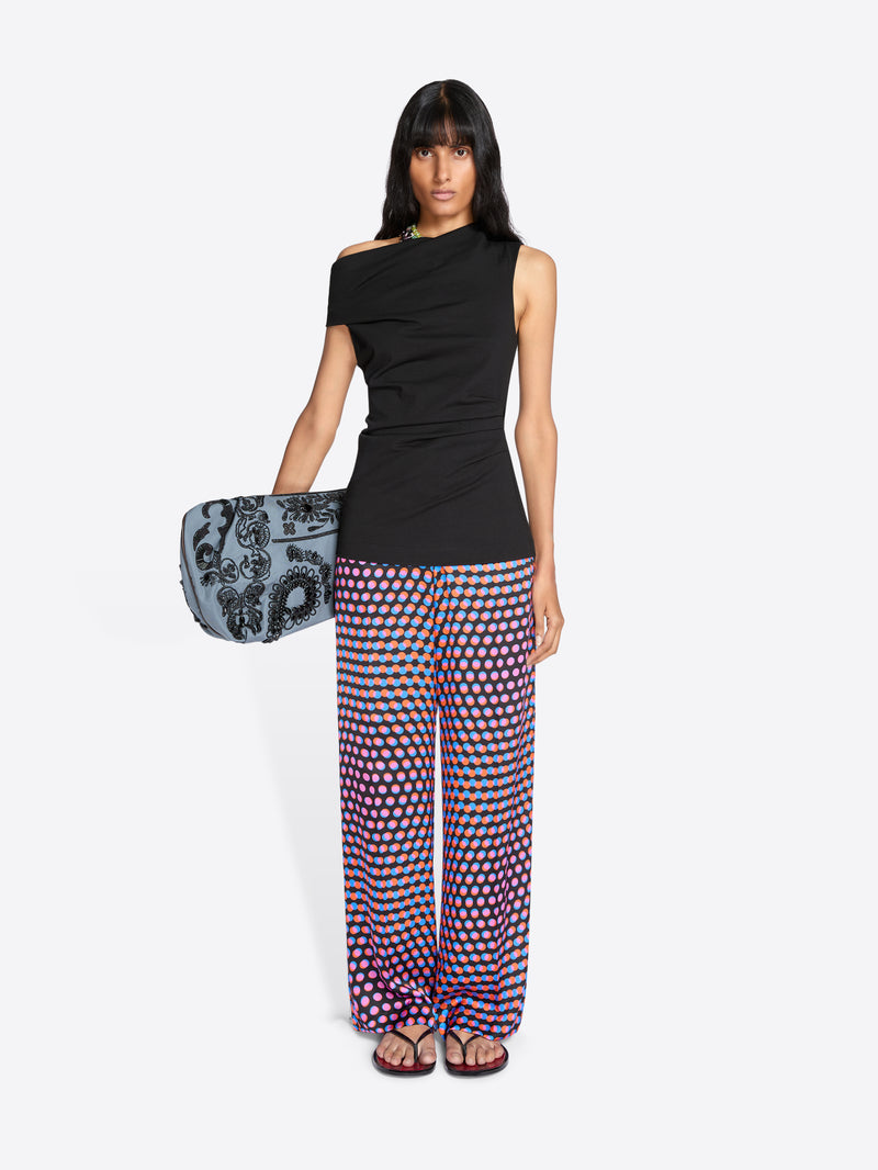 Woman wearing a black top and patterned pants holding a clutch on a white background - Dries Van Noten