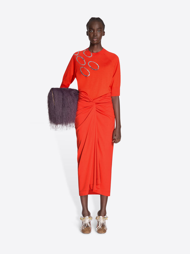 Model wearing a bright orange set with a textured clutch on a white background - Dries Van Noten