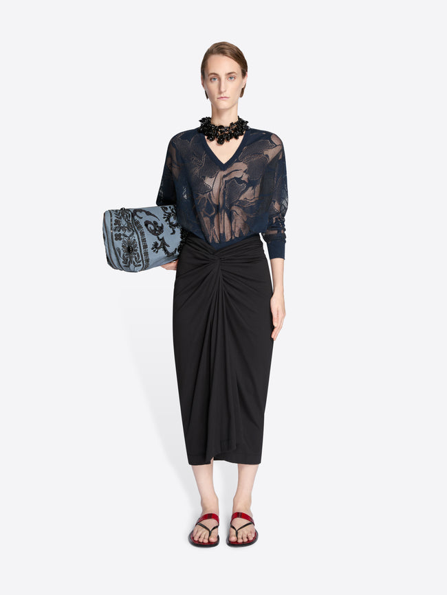 Model wearing a black lace top and black skirt holding a matching handbag on a white background - Dries Van Noten
