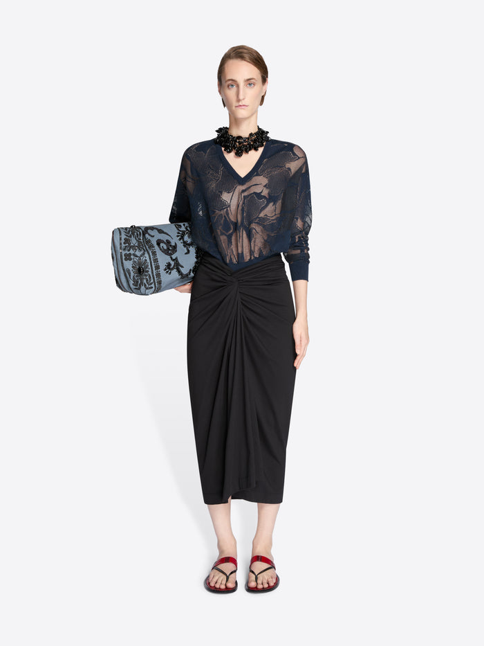 Model wearing a black lace top and black skirt holding a matching handbag on a white background - Dries Van Noten