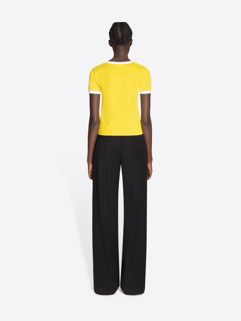 Person wearing a yellow top and black pants on a white background - Dries Van Noten
