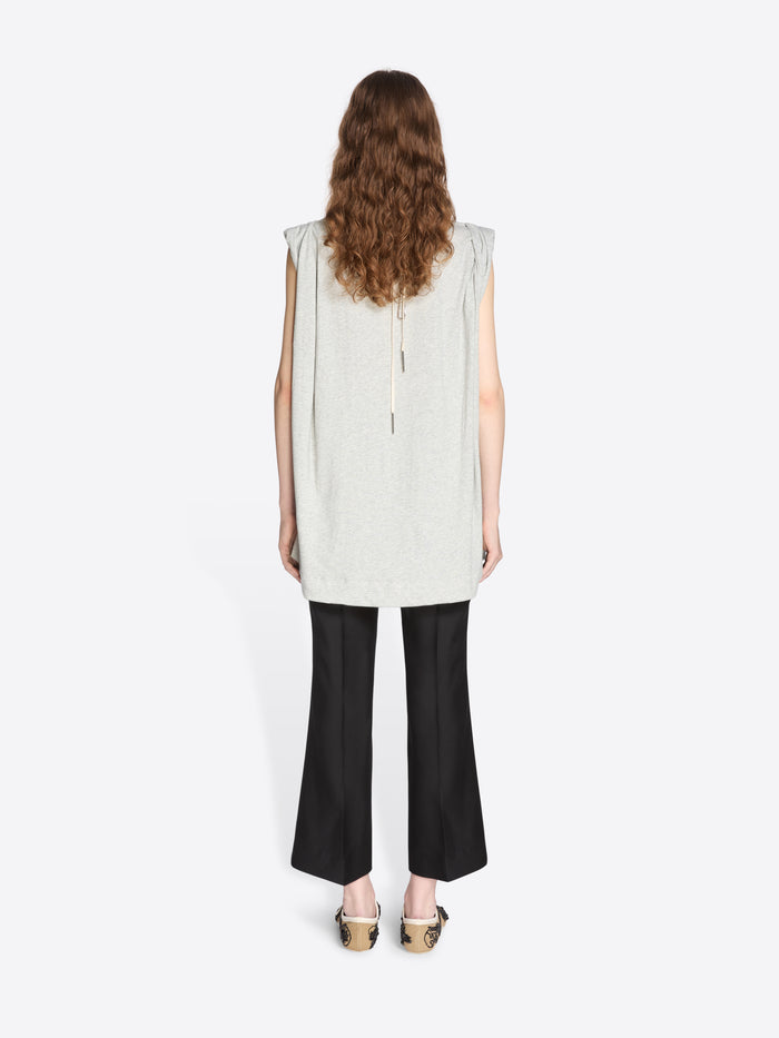 Woman wearing a white sleeveless top and black pants on a white background - Dries Van Noten
