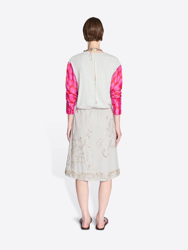 Person wearing a white top with pink sleeves and a floral skirt on a white background - Dries Van Noten