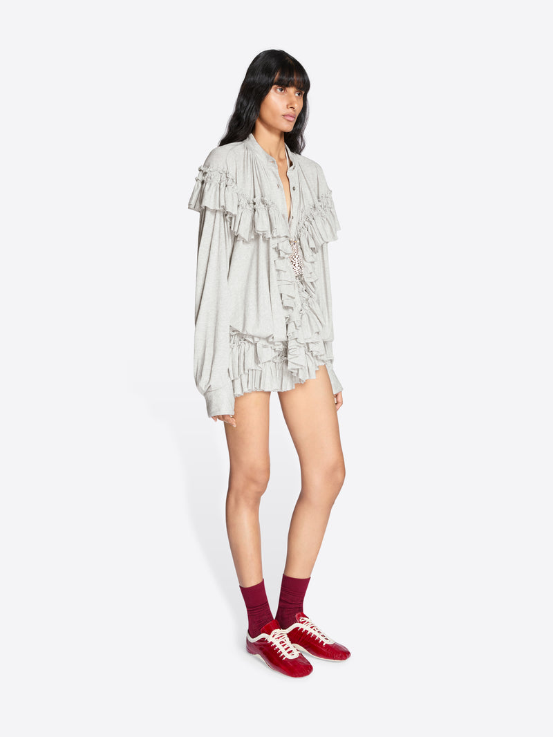 Woman wearing a light-colored ruffled dress with maroon socks and red shoes on a white background - Dries Van Noten