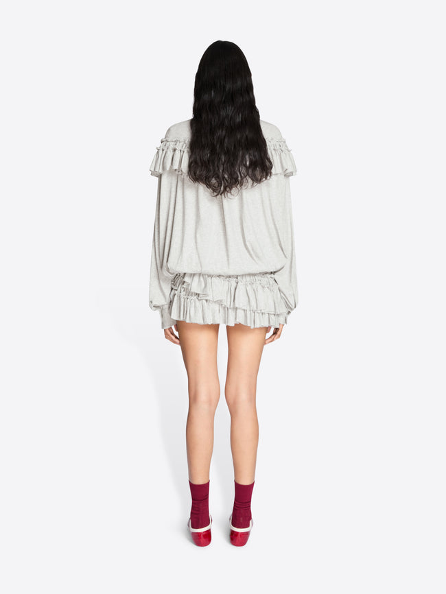 Person wearing a light-colored dress with ruffled layers on a white background - Dries Van Noten
