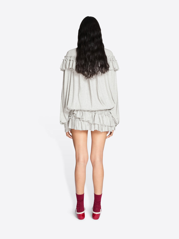 Person wearing a light-colored dress with ruffled layers on a white background - Dries Van Noten