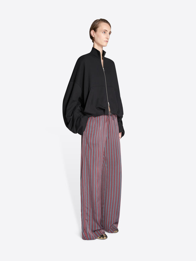 Person wearing a black jacket and striped pants on a white background - Dries Van Noten